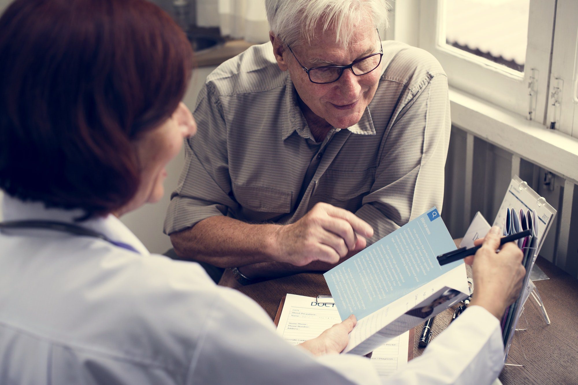 Happy elderly patient meeting with doctor to discuss the good and bad of Medicare Advantage.