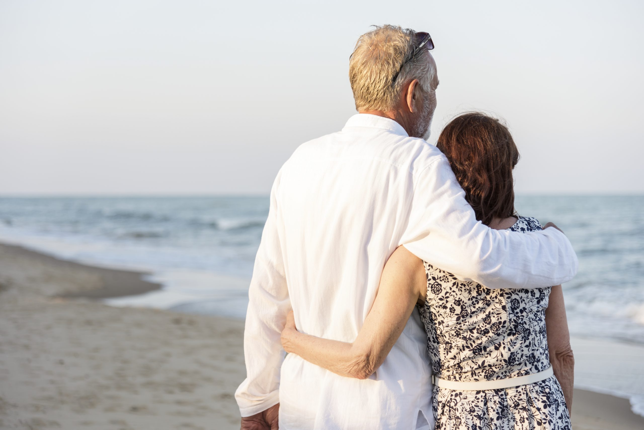 Senior couple on the beach enjoying the sunrise and relaxing waves as they talk about getting Medicare Plan G.
