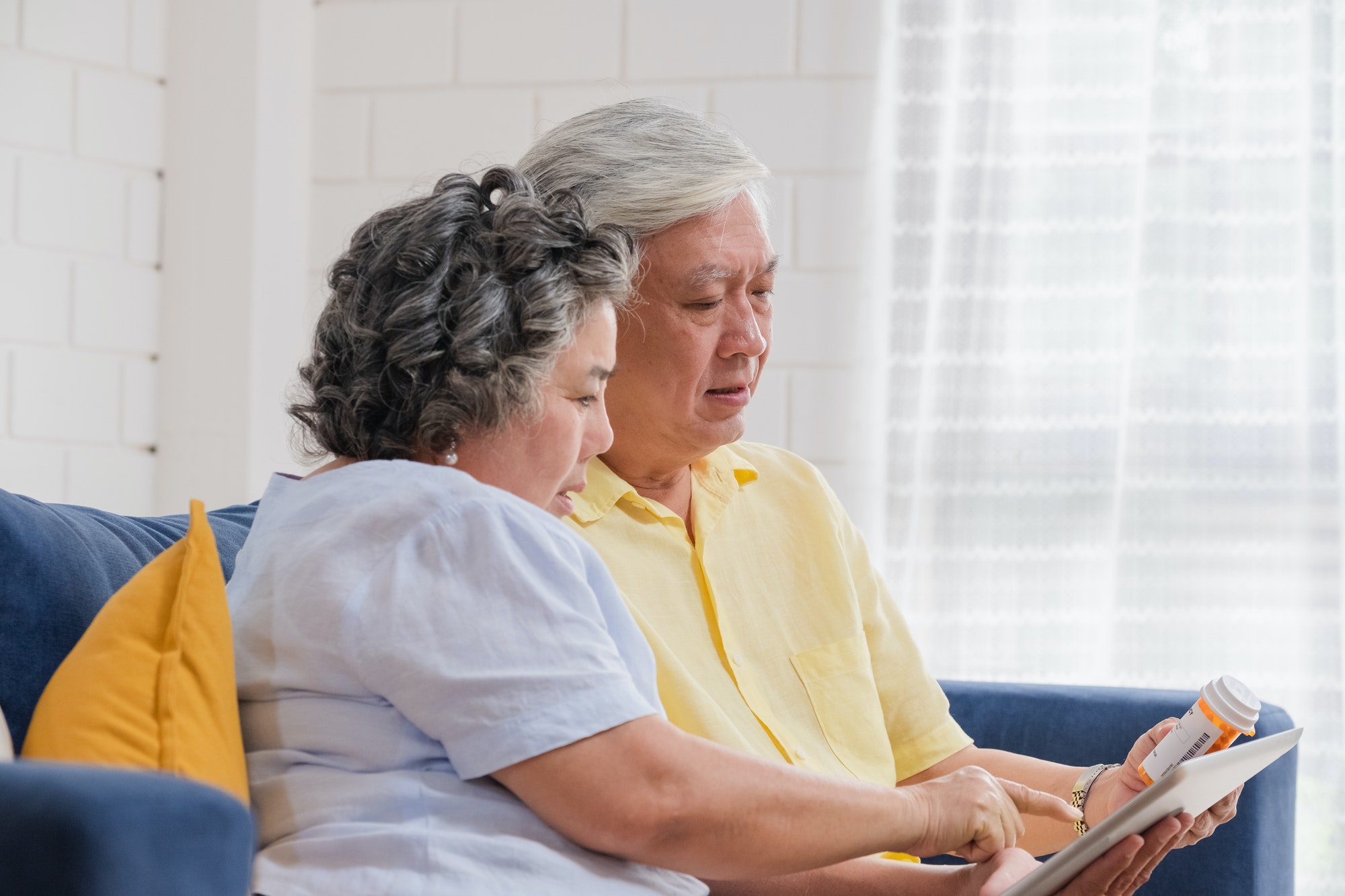 Asian senior couple use tablet searching prescription of pill avoiding the Medicare Donut Hole